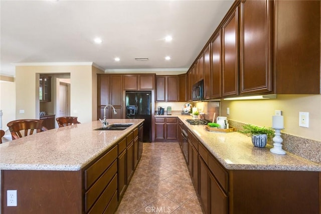 kitchen featuring a center island with sink, black appliances, light stone countertops, and sink