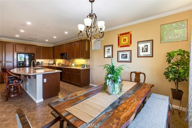 kitchen featuring black refrigerator with ice dispenser, crown molding, sink, pendant lighting, and an island with sink