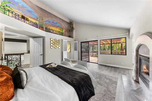 bedroom with access to outside, light hardwood / wood-style floors, and high vaulted ceiling