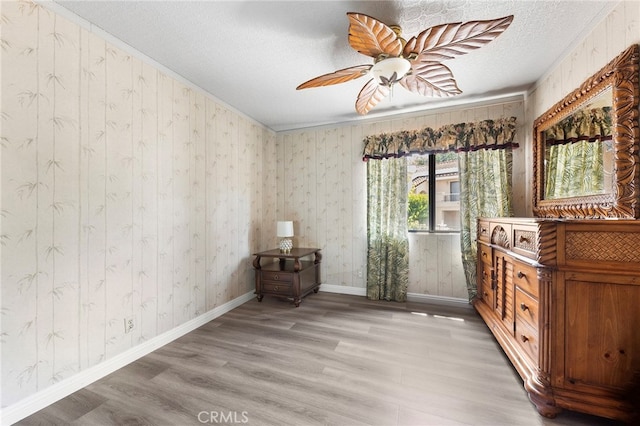 interior space with a textured ceiling, crown molding, light hardwood / wood-style floors, and ceiling fan