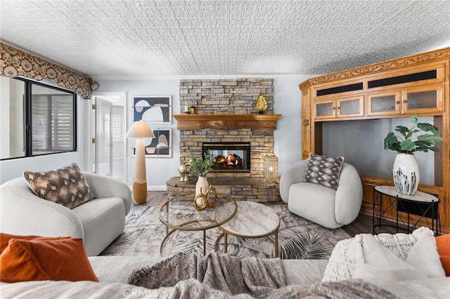 living room featuring a stone fireplace, a textured ceiling, crown molding, and light hardwood / wood-style floors