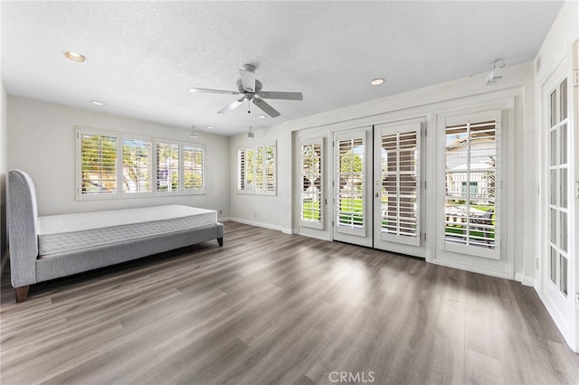 interior space with a textured ceiling, a healthy amount of sunlight, ceiling fan, and wood-type flooring