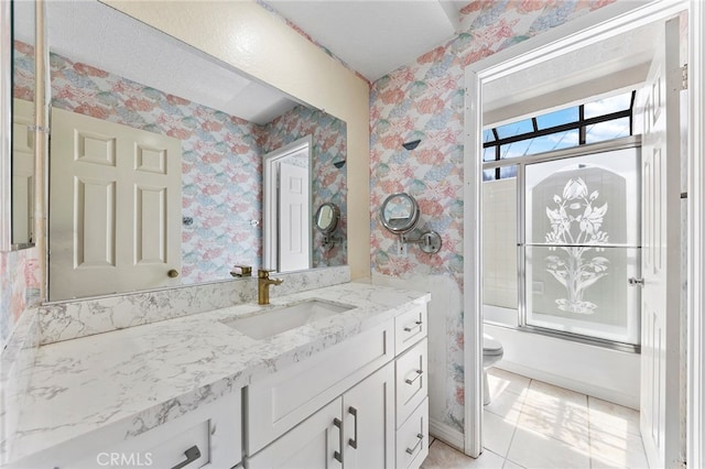 full bathroom with tile patterned flooring, bath / shower combo with glass door, vanity, and toilet