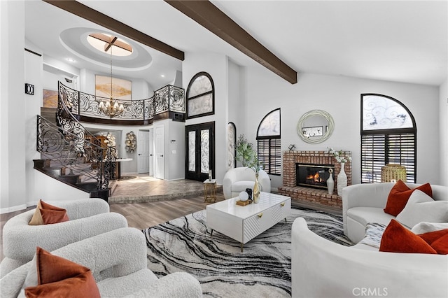 living room featuring wood-type flooring, a notable chandelier, beam ceiling, a fireplace, and high vaulted ceiling