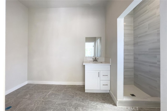 bathroom with a tile shower and vanity