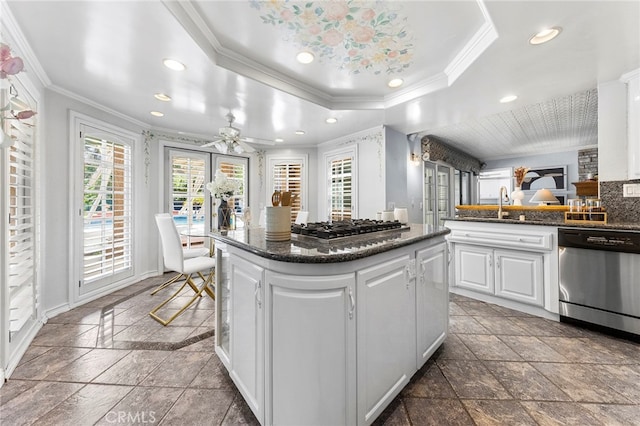 kitchen featuring white cabinets, appliances with stainless steel finishes, ornamental molding, and a tray ceiling