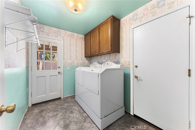 clothes washing area featuring cabinets, a textured ceiling, and washer and dryer