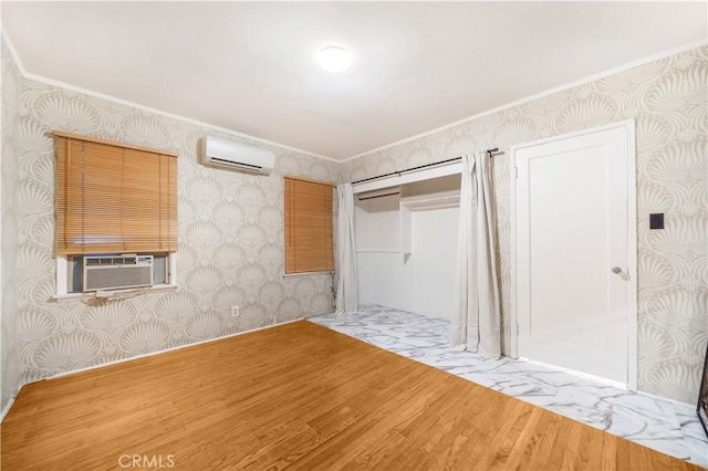 unfurnished bedroom with hardwood / wood-style floors, cooling unit, an AC wall unit, crown molding, and a closet