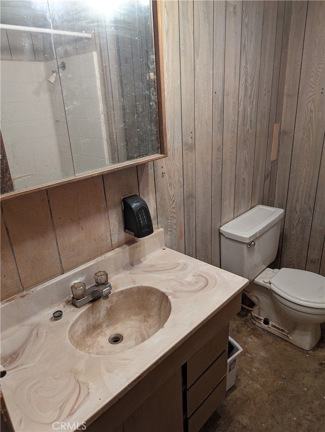 bathroom with vanity, toilet, and wooden walls