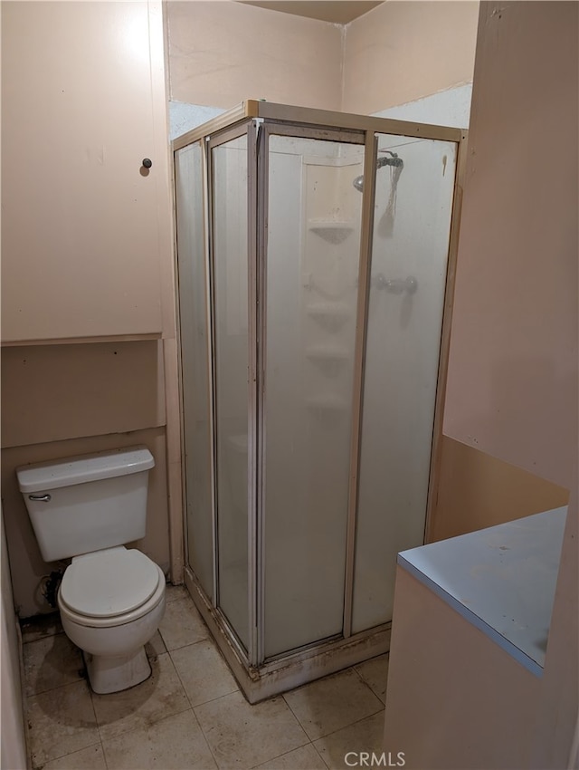 bathroom with tile patterned flooring, toilet, and an enclosed shower