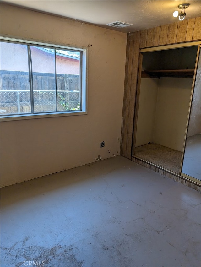 unfurnished bedroom with concrete flooring and a closet