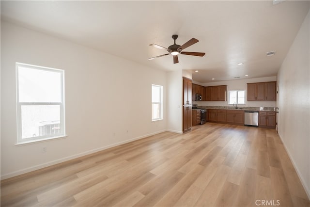 unfurnished living room featuring sink, light wood-type flooring, and ceiling fan