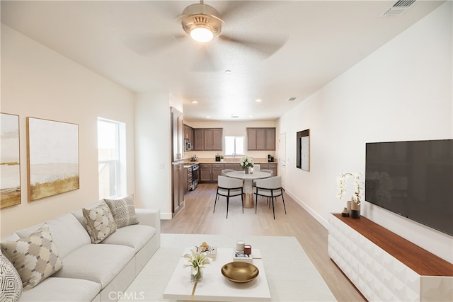 living room featuring light hardwood / wood-style flooring and ceiling fan