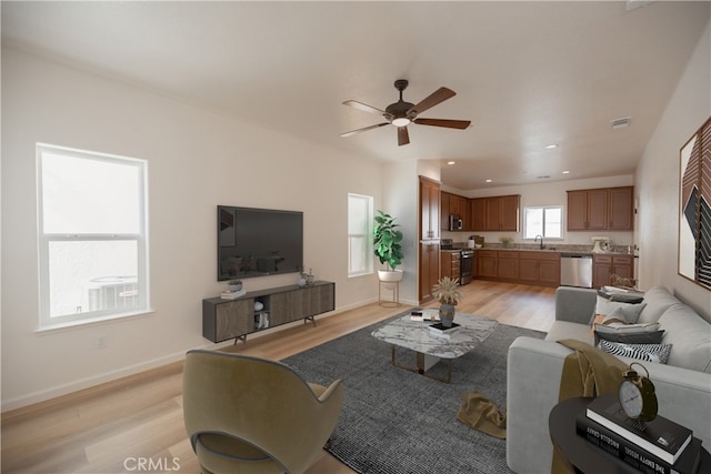 living room featuring ceiling fan, sink, and light hardwood / wood-style floors