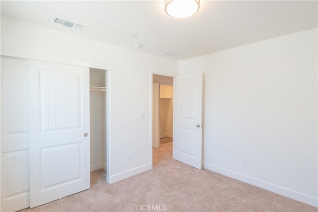 unfurnished bedroom featuring a closet and light colored carpet