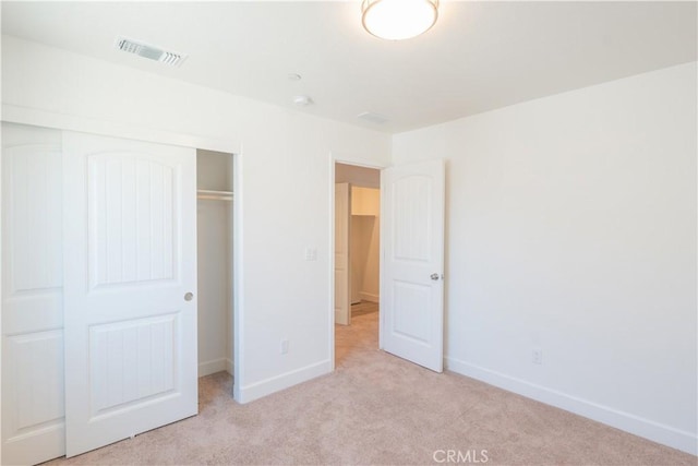 unfurnished bedroom featuring visible vents, baseboards, a closet, and light colored carpet