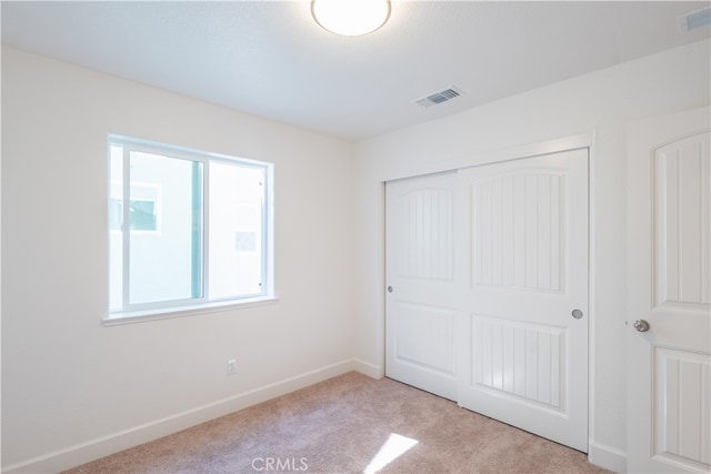 unfurnished bedroom with light colored carpet and a closet