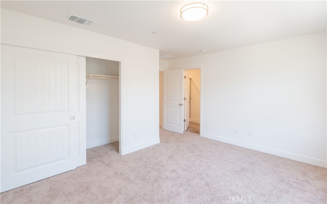 unfurnished bedroom with a closet and light colored carpet