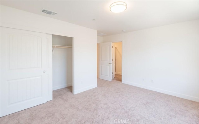 unfurnished bedroom featuring a closet, visible vents, light colored carpet, and baseboards