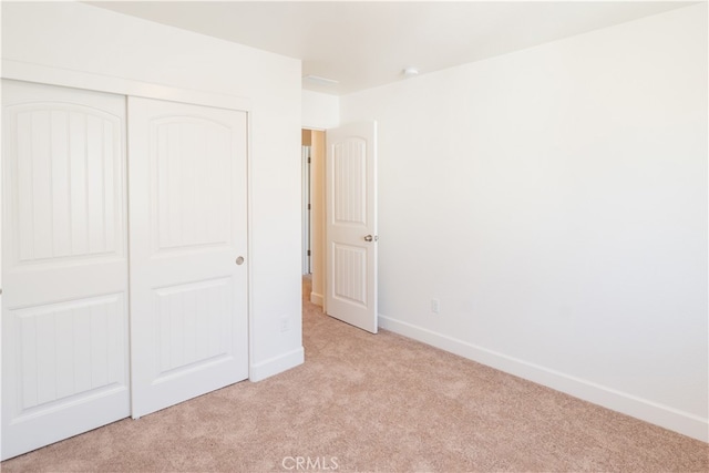 unfurnished bedroom featuring a closet and light colored carpet