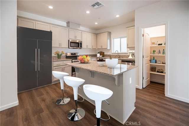 kitchen featuring a center island, dark hardwood / wood-style floors, stainless steel appliances, and light stone counters