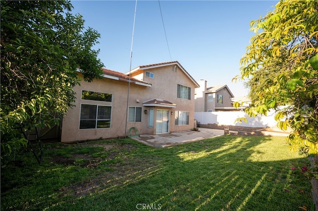 rear view of property featuring a lawn and a patio