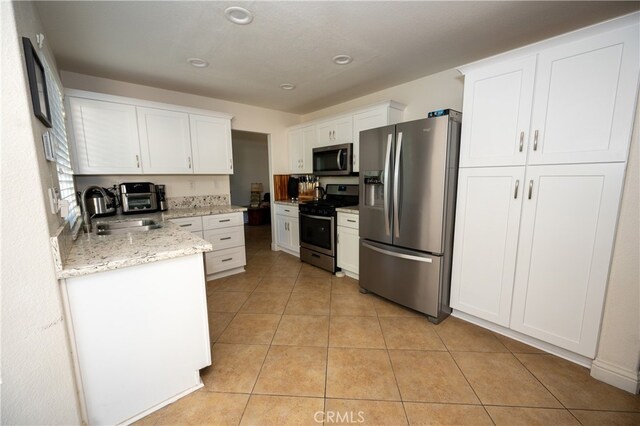 kitchen featuring white cabinets, light stone counters, appliances with stainless steel finishes, and sink