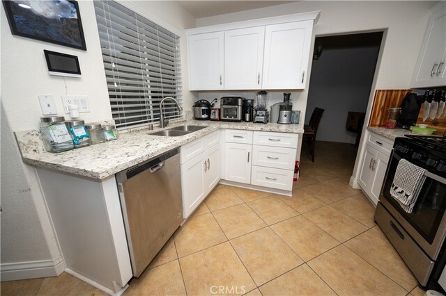 kitchen with white cabinets, light stone counters, appliances with stainless steel finishes, and sink