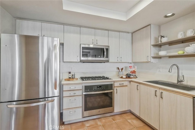 kitchen featuring a raised ceiling, appliances with stainless steel finishes, sink, and light tile patterned floors