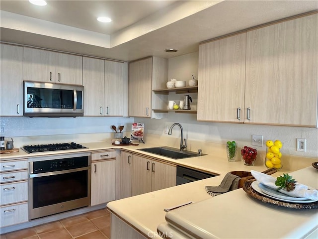 kitchen featuring sink, stainless steel appliances, light tile patterned flooring, light brown cabinetry, and a raised ceiling