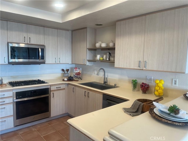 kitchen with sink, tile patterned flooring, stainless steel appliances, a tray ceiling, and light brown cabinets