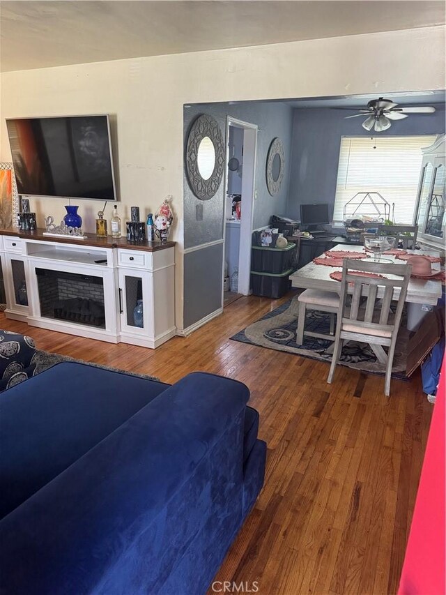 2016 W 103rd St, Los Angeles, CA 90047 - living room with wood finished floors, ceiling fan, a fireplace, a desk, and baseboards
