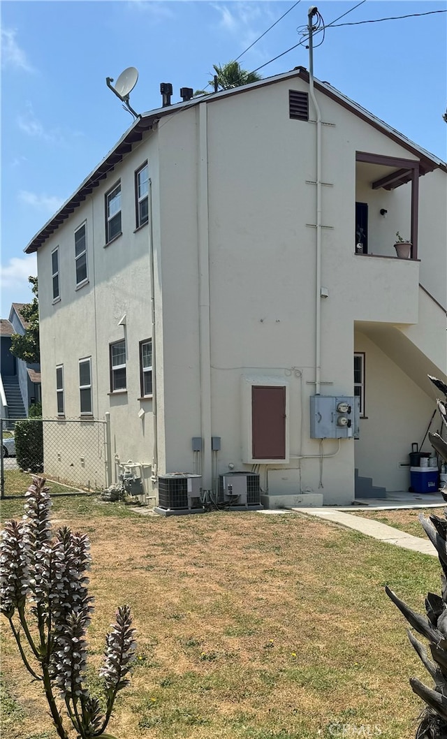 rear view of property with central AC and a yard