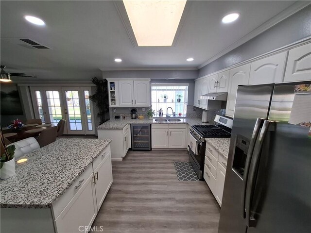 kitchen with sink, beverage cooler, stainless steel appliances, tasteful backsplash, and white cabinets