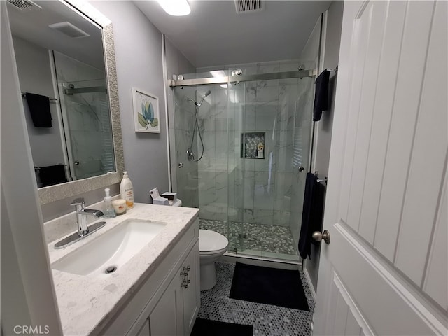 bathroom featuring tile patterned floors, vanity, toilet, and a shower with door