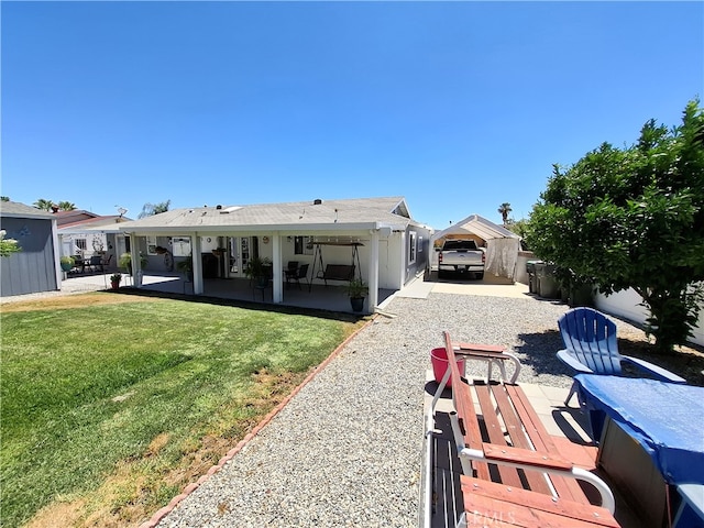 back of house with a lawn and a patio