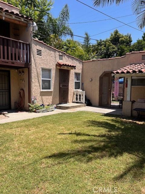 rear view of property featuring a balcony and a yard