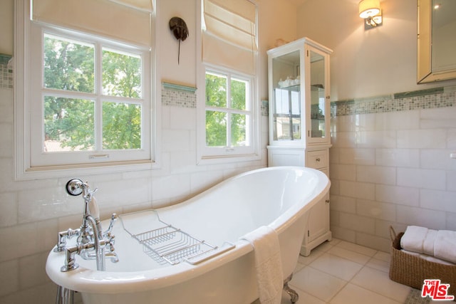 bathroom with tile walls, a bath, and tile patterned flooring