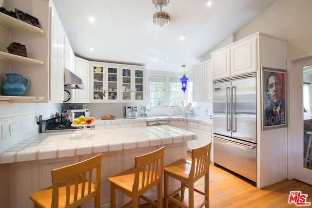 kitchen featuring tile countertops, stainless steel appliances, backsplash, and white cabinets