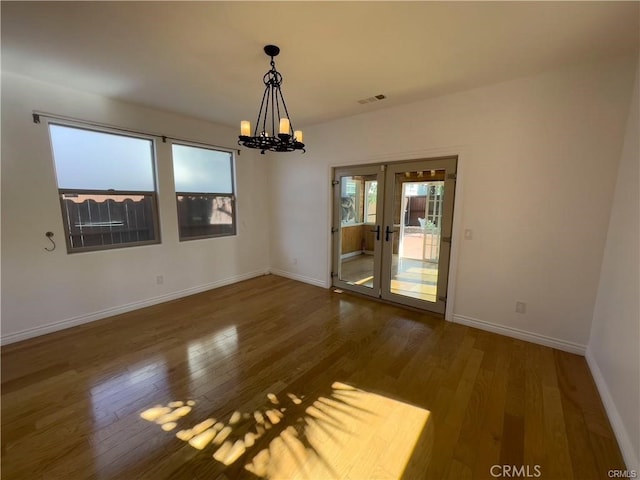 empty room featuring hardwood / wood-style floors, an inviting chandelier, and french doors