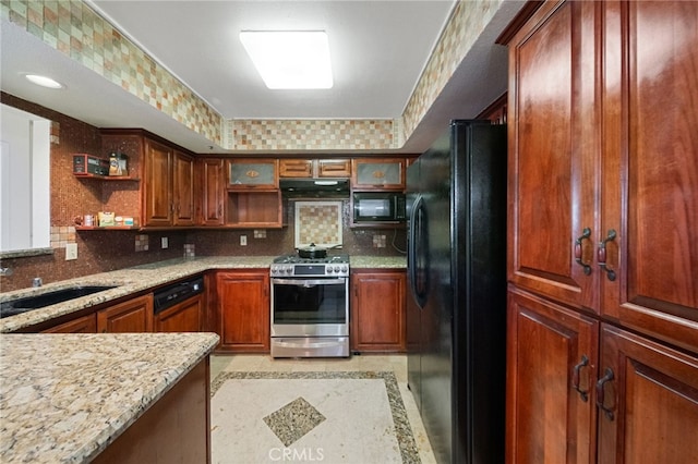 kitchen featuring black appliances, decorative backsplash, light stone countertops, and sink