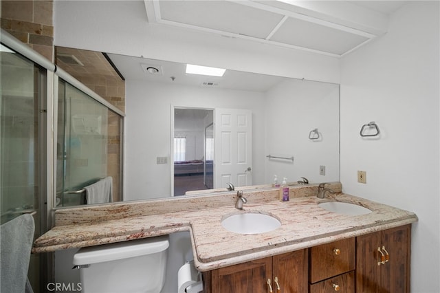 bathroom featuring a shower with shower door, vanity, and toilet