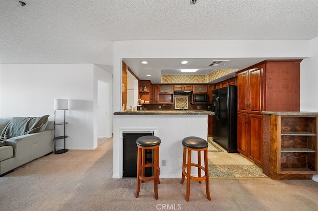 kitchen with kitchen peninsula, black appliances, a textured ceiling, and light colored carpet