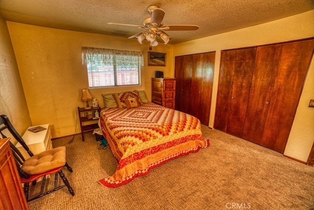 bedroom featuring two closets, ceiling fan, carpet floors, and a textured ceiling