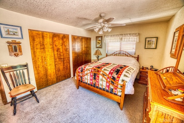 bedroom with multiple closets, ceiling fan, carpet, and a textured ceiling