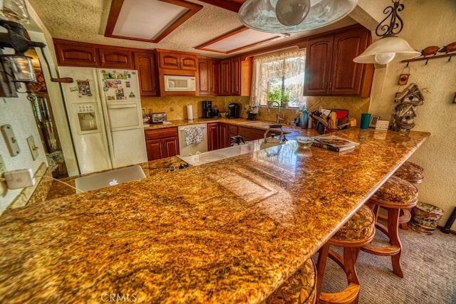 kitchen featuring kitchen peninsula, a kitchen breakfast bar, white appliances, and sink