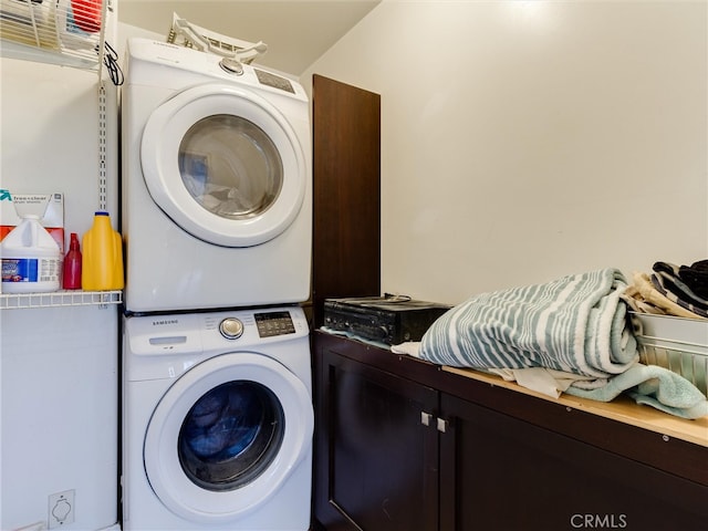 laundry room featuring cabinets and stacked washing maching and dryer