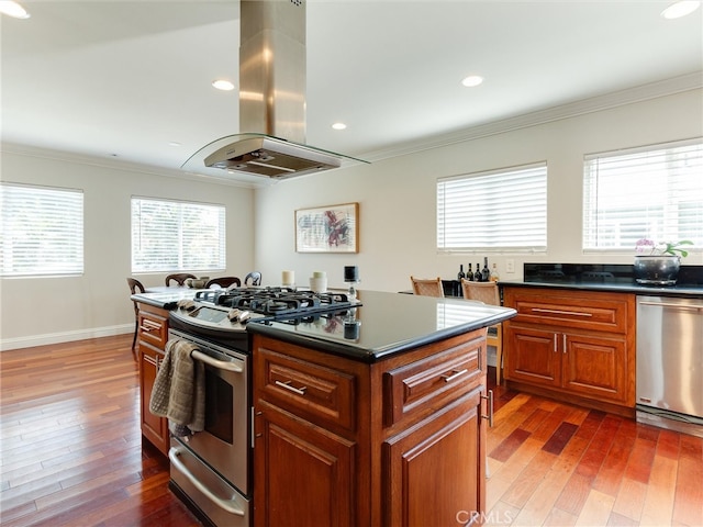 kitchen featuring ornamental molding, island exhaust hood, appliances with stainless steel finishes, dark hardwood / wood-style floors, and a center island