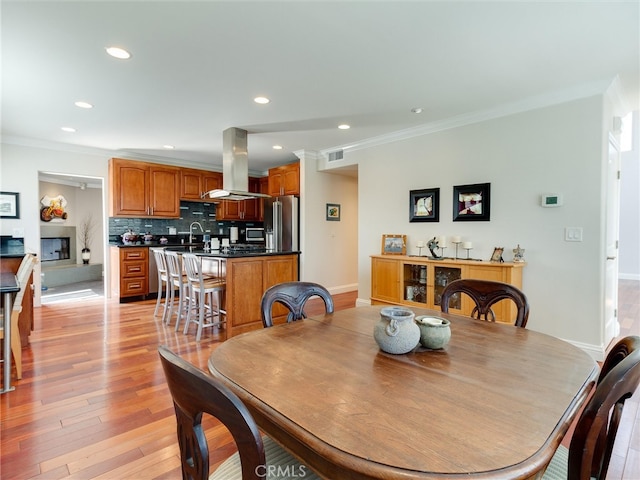 dining room featuring light hardwood / wood-style flooring, sink, and crown molding