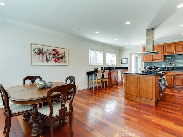 dining area with crown molding, sink, and hardwood / wood-style flooring